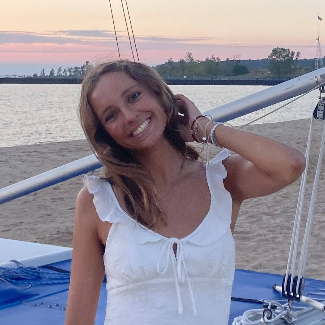 Lauren Elias poses by a beached sailboat at sunset.